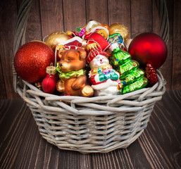 Christmas or New Year background: basket with colored glass toys and balls, decoration and gifts on wooden background
