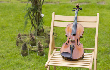 A beautiful violin on a chair outdoors. The concert on the open air. Festive concert. Wedding ceremony. Violin
