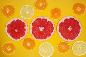 Various slices of citrus fruits on the bright yellow background