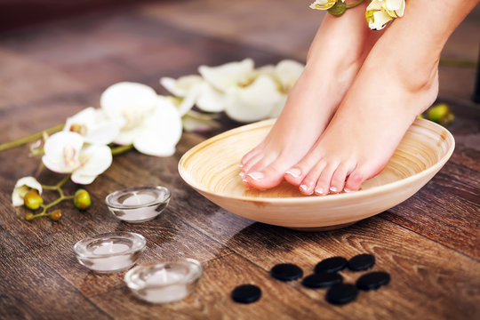 Woman washing beautiful legs in bowl, on light background. Spa p