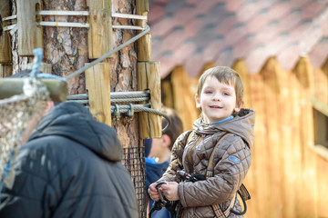 Obraz premium Cute child, boy, climbing in a rope playground structure
