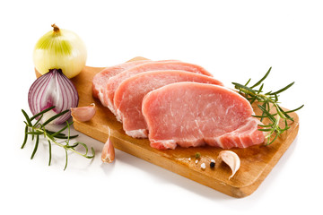 Raw pork chops on cutting board and vegetables 