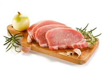 Raw pork chops on cutting board and vegetables