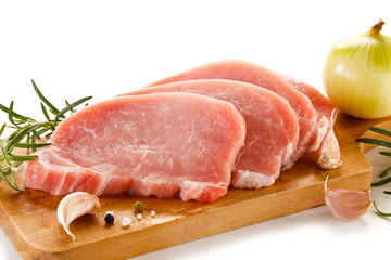 Raw pork chops on cutting board and vegetables