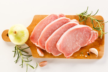 Raw pork chops on cutting board and vegetables
