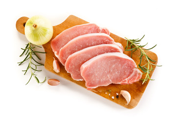 Raw pork chops on cutting board and vegetables