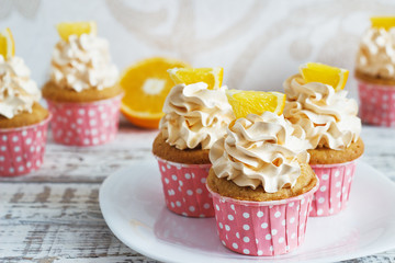 Vanilla cupcakes with a cap of cream on white wooden table