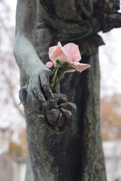 Melancholy. Hand of statue with a bronze and an artificial rose