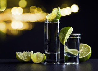 Gold tequila and lime on black table