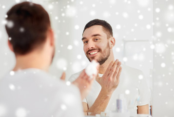 happy man applying shaving foam at bathroom mirror