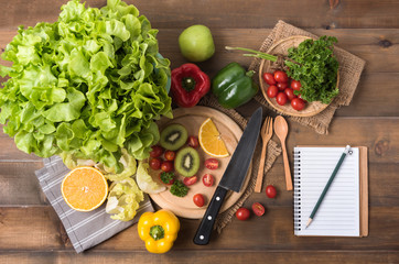 vegetables and fruit with notebook on wood background