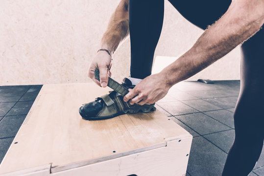 Cropped shot of man fastening trainers in cross training gym