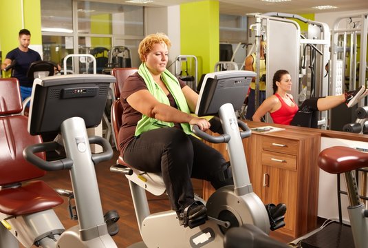 Fat Woman Training On Exercise Bike In Gym