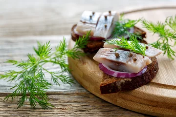 Foto op Canvas Sliced herring on rye bread with red onion. © sriba3