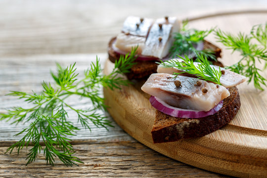 Fototapeta Sliced herring on rye bread with red onion.