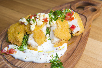 Crispy fried chicken with, tomato, cheese, ruccola, cream on wooden background