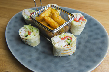 Breakfast burrito , wrapped burrito, fried potato wedges in plate on wooden background