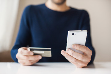 Male hands holding credit card and using smart phone. Online shopping concept