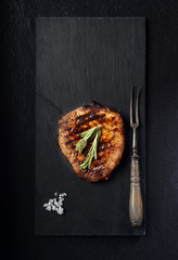 grilled beef steak on a black slate board. On a black background

