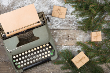 Christmas concept - workplace with a typewriter, spruce branches and gift boxes on a wooden table