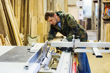 Carpenter at work on woodworking machines with a circular saw