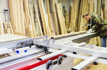 Carpenter working on woodworking machines with a circular saw