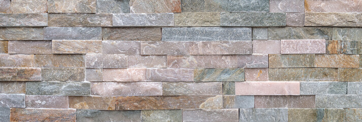 Steinwand aus groben, pastellfarbenen Verblendsteinen als Panorama