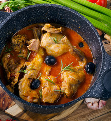 Baked rabbit  in tomato sauce with black olives and herbs.