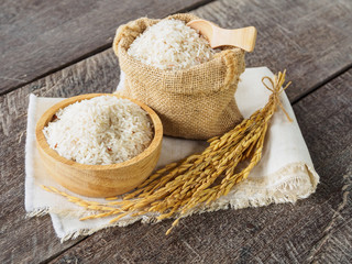Jasmine rice grain on bowl and sack with spike on old wooden bac