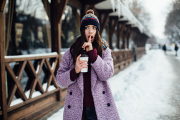 Portrait happy and beautiful girl in winter street heated coffee and smile.