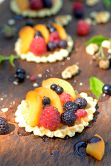 Fresh red, black raspberry and currant, peach, honey on waffle on wooden texture close up