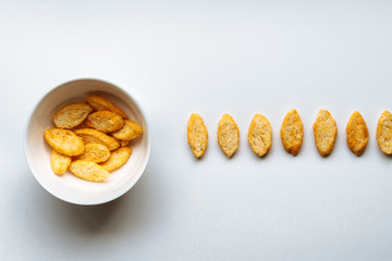 Row of toasts next to white bowl full of toast with olive oil on