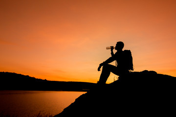 Fototapeta na wymiar Silhouette of man with backpack drinking water, travel