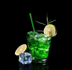 Green tarragon drink with ice cubes, lime on a black  background