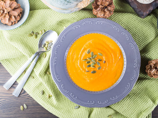 Pumpkin cream soup in dark plate. Top view