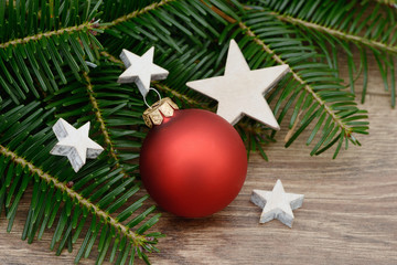 Rote Weihnachtskugel mit Tannen und Sterne  auf Holz