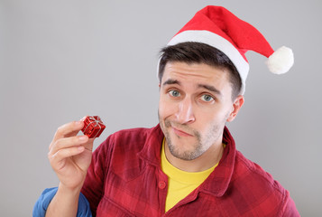 Closeup portrait unhappy, upset man holding small red gift