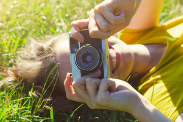 smiling girl lying in grass with film camera