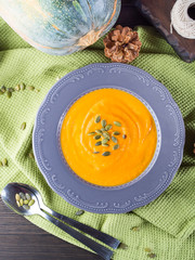Pumpkin cream soup in dark plate. Vertical