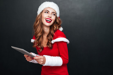 Laughing cheerful young woman holding tablet and looking away