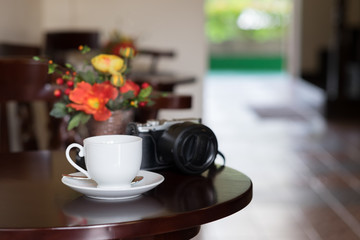 Hot coffee with camera on a wooden table. Soft focus.