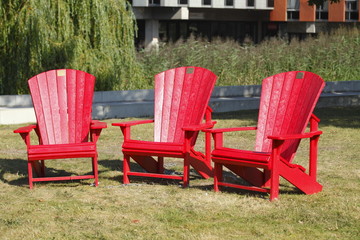 rote Holzgartenstühle auf einer Wiese