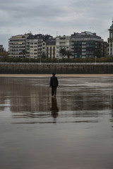 Persona mayor paseando por la orilla de una playa