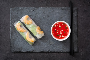 Vietnamese rolls with vegetables, rice noodles and prawns on black slate
