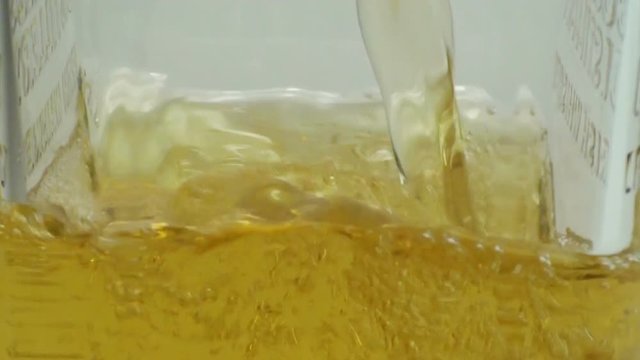 Close-up view of pouring a whiskey into glass with a splash. HD 1920x1080 video clip