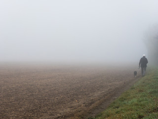 KIRKBY IN ASHFIELD, ENGLAND - OCTOBER 31: Man walking dog in fog, England. In Kirkby In Ashfield, Nottinghamshire, England. On 31st October 2016.