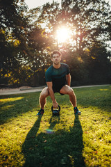Strong man exercising with kettle bell in the park