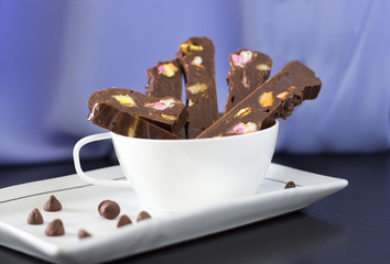 Chocolate Fudge with colorful marshmallow in a white mug on a blue and black background