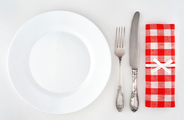 Empty plate with cutlery and red checkered napkin. Overhead view.