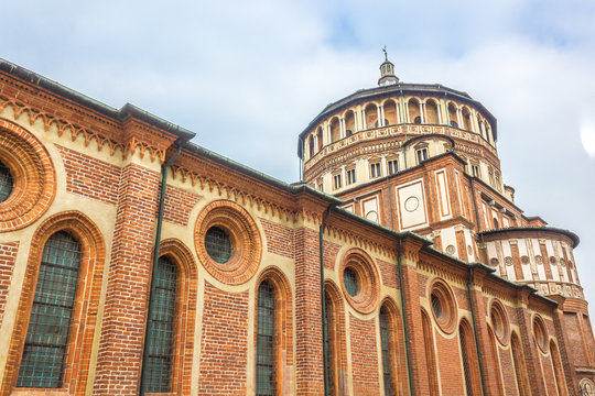 Milan's famous church Santa Maria Delle Grazie, hosting in it's refectory, The Last Supper mural painting by Leonardo da Vinci. side view with blue sky.